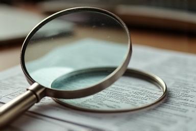 Magnifying glass over documents, representing investigation